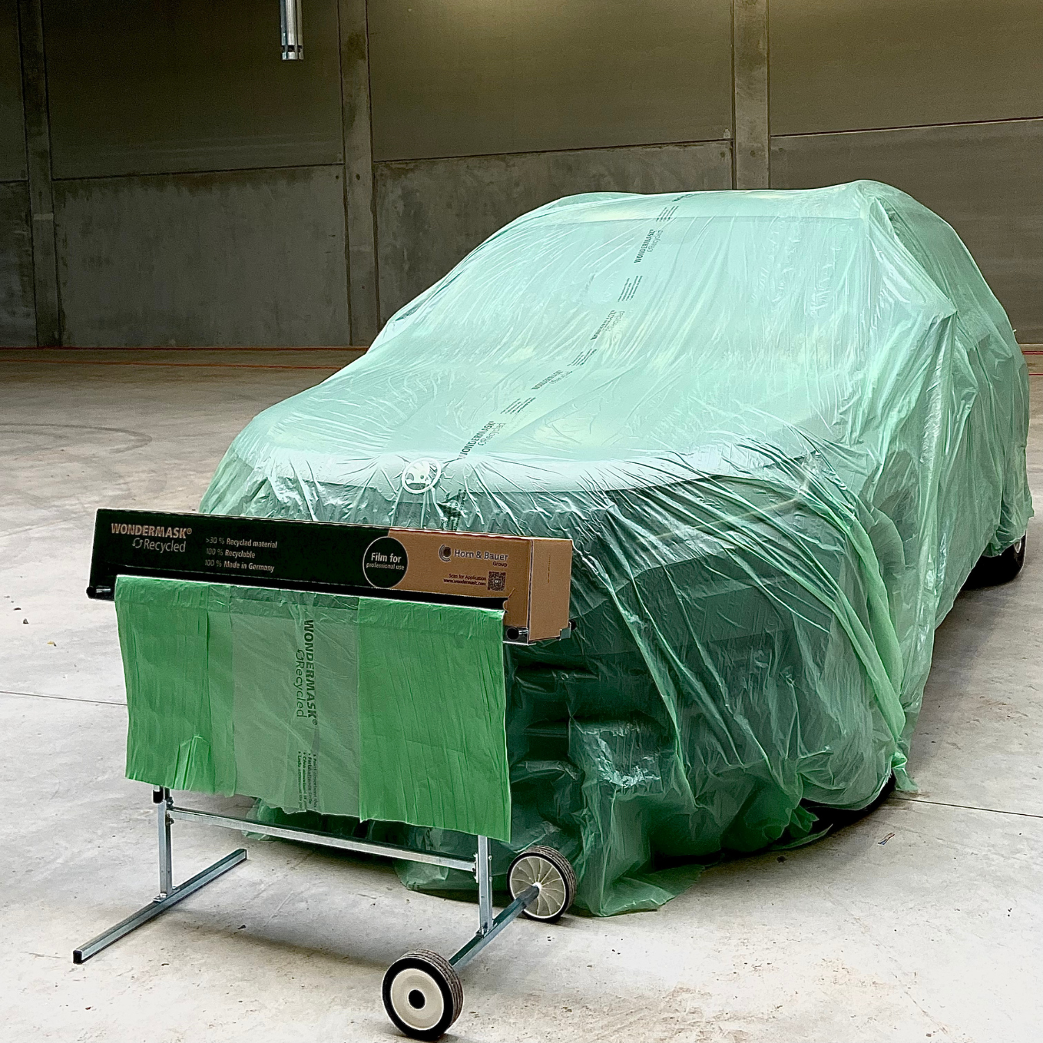  A car is covered with a green protective film from the WONDERMASK® RECYCLED. This protective film is made from over 30% recycled material and is 100% recyclable.