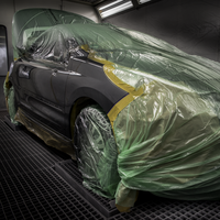 A vehicle in a paint booth is completely covered with the heat-resistant cover film WONDERMASK®***LITEPLUS, with individual body areas cut free for painting.