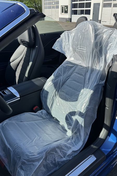 The picture shows the interior of a blue convertible with the top down. The driver’s seat is covered with the Smartgrip3in1 Eco.
